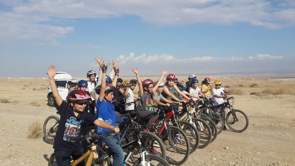 קבוצת רוכבי אופניים מצטלמים עם אופני הרים על שביל מדברי